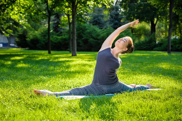 Νεαρή γυναίκα να κάνει ασκήσεις γιόγκα στο πάρκο της πόλης το καλοκαίρι. — Φωτογραφία Αρχείου