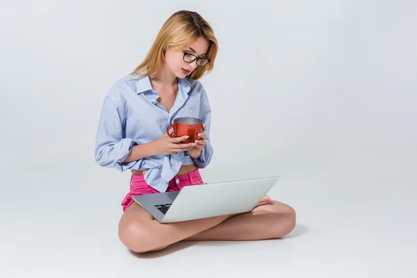 Молода жінка сидить на підлозі і використовує ноутбук — стокове фото