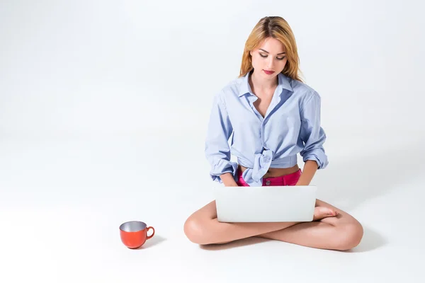 Ung kvinna som sitter på golvet och använder laptop — Stockfoto