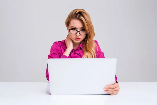 Ung kvinna sitter i tabellen och använder bärbar dator — Stockfoto