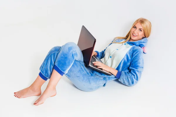 Flicka i pyjamas med en laptop på golvet — Stockfoto