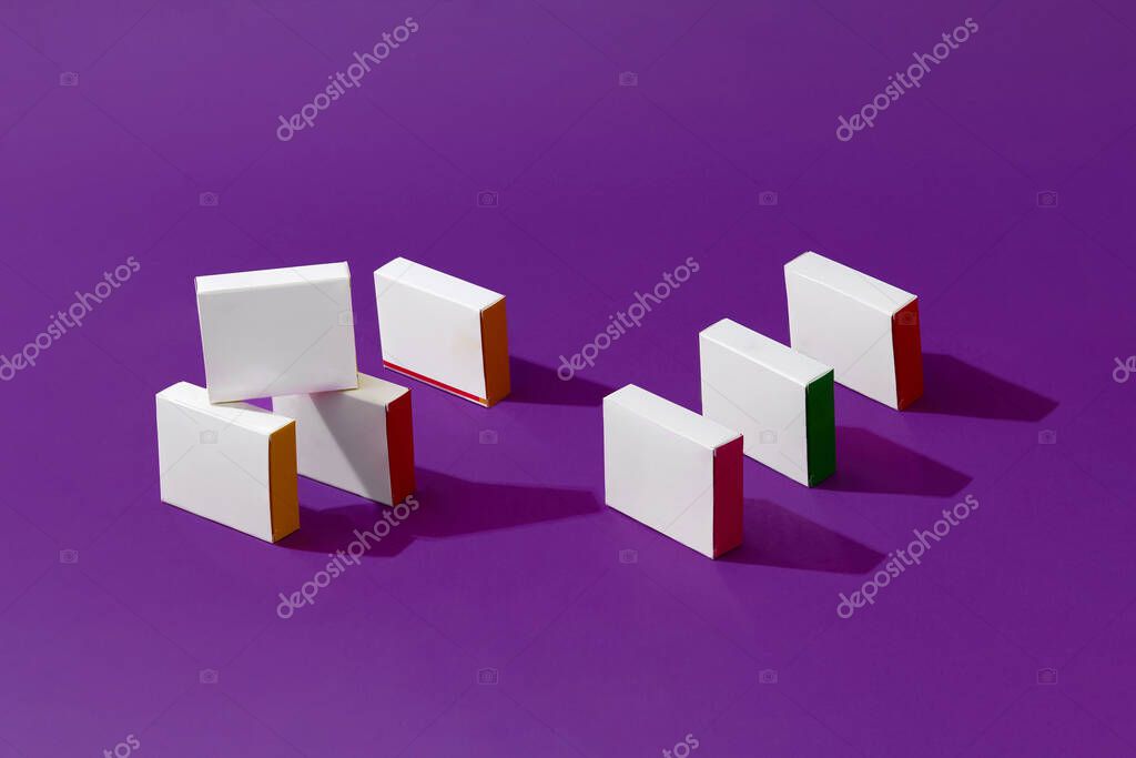 Seven small shadow-casting white cardboard boxes or packs with colorful sides and no logo on purple studio background. Branding area. Mock up, advertising. Close up, copy space