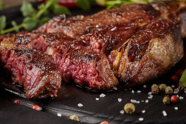 Sluiten van gesneden rundvlees entrecote met specerijen en groenten — Stockfoto