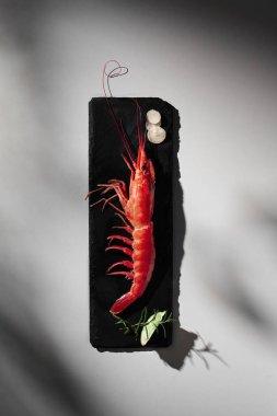 Gri arkaplanlı ve gölgeli soslu tam kırmızı karides.