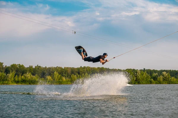 Чоловік, який стрибає над водою створюючи бризки — стокове фото