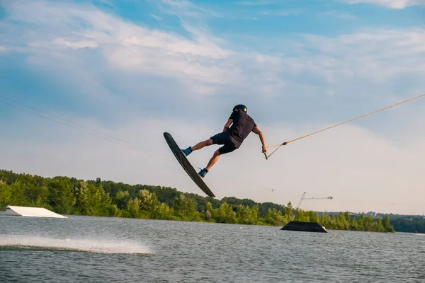 Ung man hoppar över vattenytan av floden på wakeboard — Stockfoto