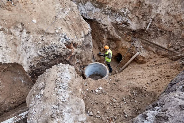 Працівник викопує траншею з лопатою в котлован для встановлення зв'язку з новою багатоповерховою будівлею — стокове фото