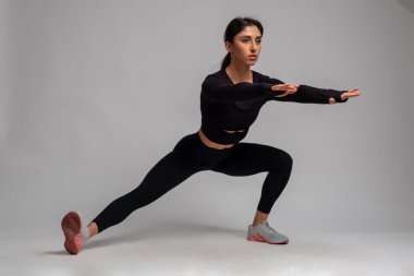 Fit esmer, gri arka planda vücut ağırlığı hareketleri yapıyor.