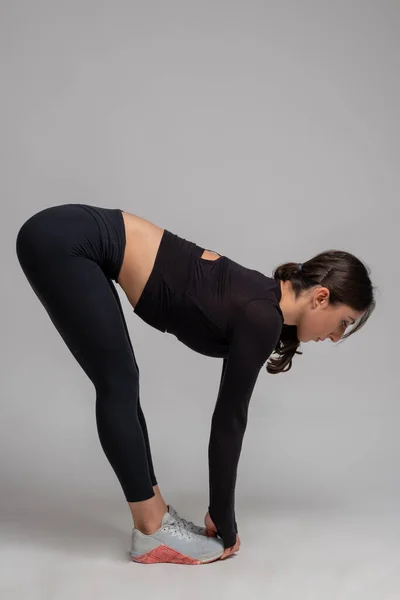 Vrouw doen stretching naar voren bochten op grijze achtergrond — Stockfoto