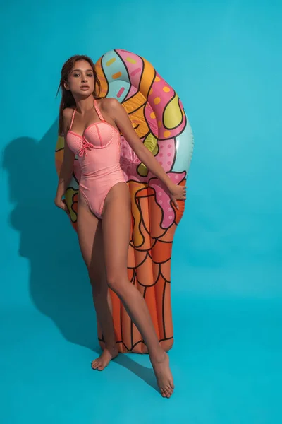 Chica en traje de baño sobre fondo azul con colchón inflable — Foto de Stock