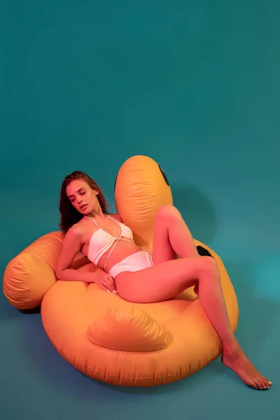 Junge Frau im Bikini sitzt auf gelbem aufblasbarem Spielzeug — Stockfoto