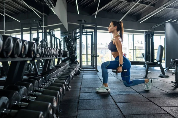 Sporcu kız spor salonunda dambıllarla hamle yapıyor. — Stok fotoğraf