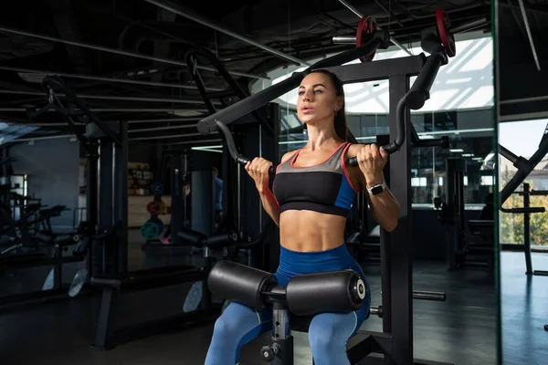 Mädchen macht Übungen für die Rückenmuskulatur an Kraftgeräten im Fitnessstudio — Stockfoto