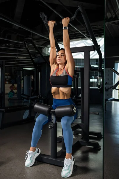 Mädchen macht Rückwärtsgriff hohe Hebelreihe an Kraftgerät im Fitnessstudio — Stockfoto