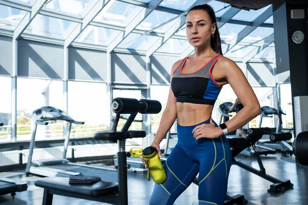 Mädchen steht nach dem Training mit Wasserflasche im Fitnessstudio — Stockfoto