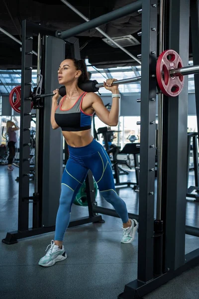 Woman doing reverse lunges on Smith machine at gym