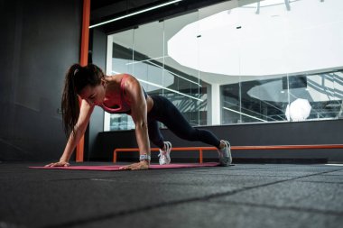 Athletic woman performing push-ups during training at gym