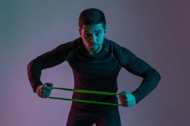 Athletic guy stretching resistance elastic band with hands