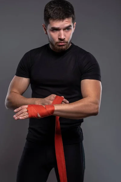 Young kickboxer wrapping bandages on hands before training — Fotografia de Stock