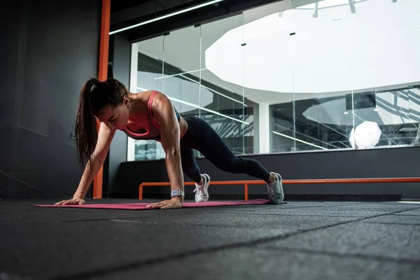 Athletic woman performing push-ups during training at gym — Foto Stock