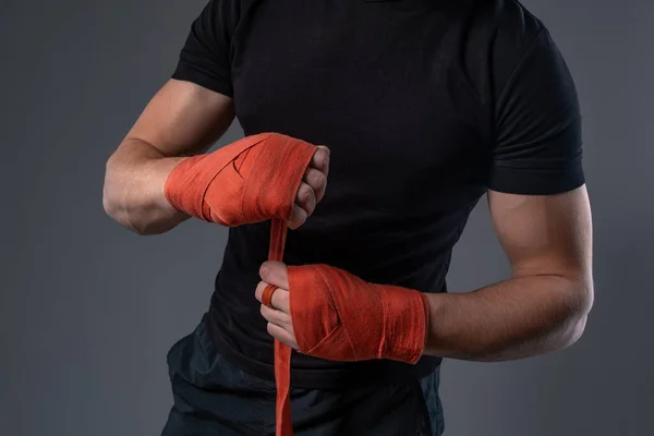 Man wrapping hands with red tape, preparing for boxing — Stockfoto