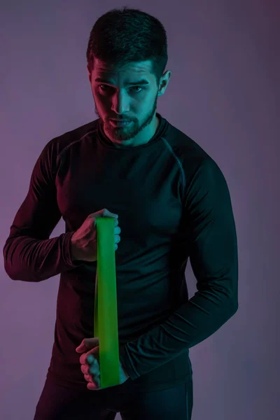 Athletic young man performing exercises with resistance band — Stockfoto