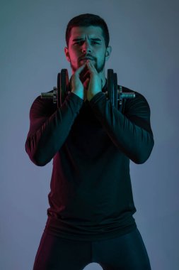 Dambılı gri arka planda odaklanmış genç bir adam.