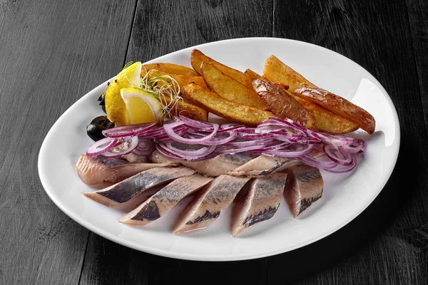 Arenque salgado com fatias de batata frita, cebola e limão — Fotografia de Stock