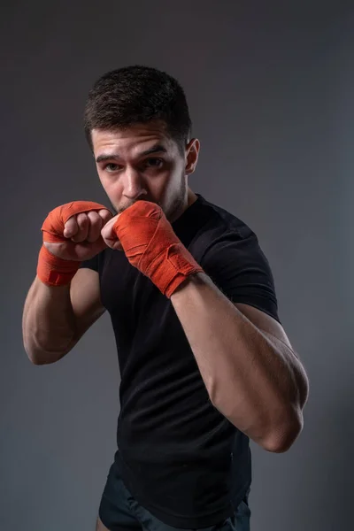 Boxeador joven con vendajes rojos en las manos posando en postura ortodoxa — Foto de Stock