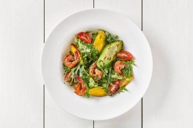 Roka salatası, domates, mango, avokado ve soslu karides.