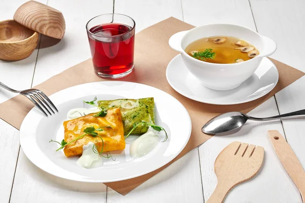 Mittagessen mit Pilzsuppe, Spinat-Karotten-Crêpes mit saurer Sahne, Beerengetränk — Stockfoto