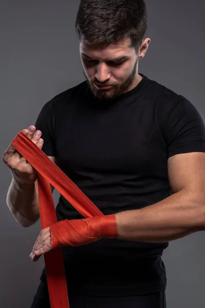 Jovem envolvendo pulsos com fita vermelha de boxe — Fotografia de Stock