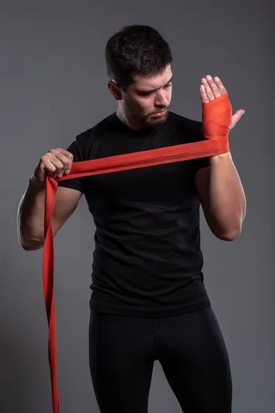 Young man wrapping hands with red boxing hands tape — Stockfoto