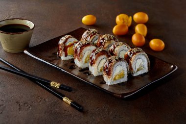 Sushi rolls with eel, cream cheese, orange, unagi sauce and sesame clipart