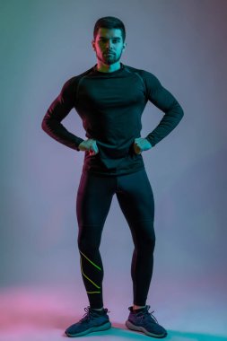 Atletik genç adam öne doğru poz veriyor.