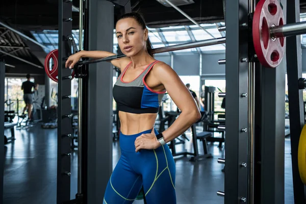 Confident athletic girl standing near Smith machine at gym — Stockfoto
