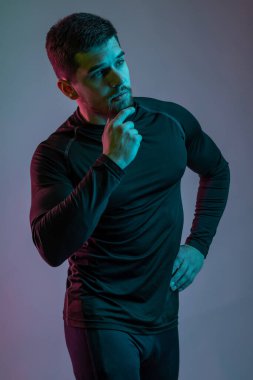 Gri arka planda poz veren düşünceli genç bir sporcu.