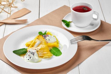 Ekşi kremalı krep, pudra şekeri ve meyve çayı.