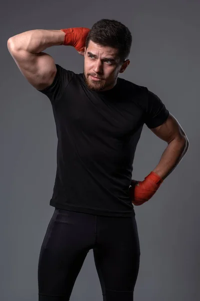 Junger Mann in Sportbekleidung mit Handschellen auf grauem Hintergrund — Stockfoto