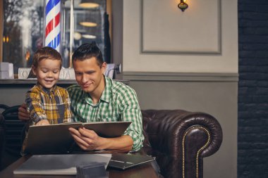 Genç baba ve şık oğlu bekleme odasındaki berber dükkanında..