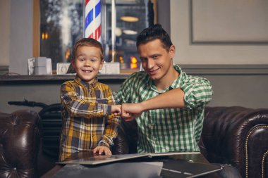 Genç baba ve şık oğlu bekleme odasındaki berber dükkanında..