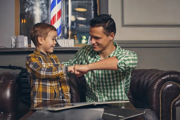 Jovem pai e seu filho na barbearia na sala de espera. — Fotografia de Stock