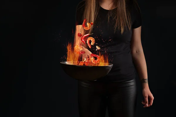 女性の手で鍋の上に火の中にホバリングエビの尾や野菜 — ストック写真
