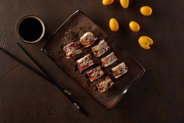 Yılan balığı, krem peynir, kumkat ve unagi soslu suşi.