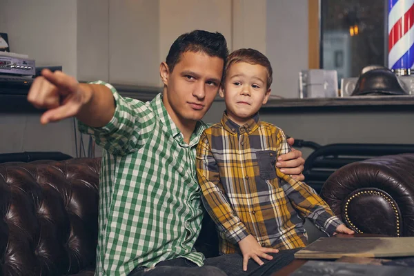 Молодий батько і його стильний маленький син в перукарні в залі очікування . — стокове фото