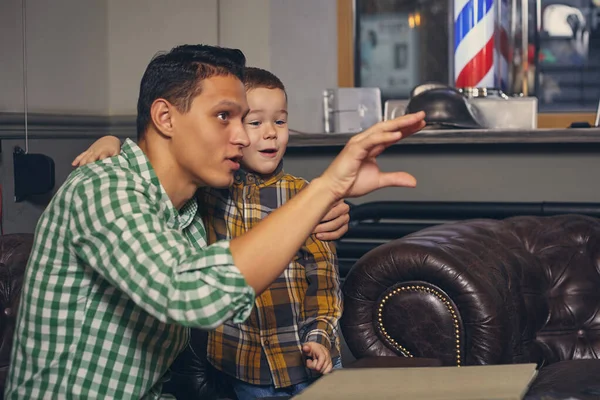 Jovem pai e seu filho na barbearia na sala de espera. — Fotografia de Stock