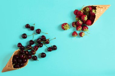 Mavi arka planda waffle kornasında çilek ve kirazlar