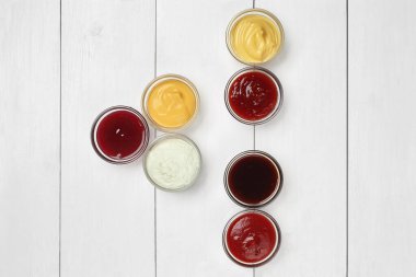 Various sauces in glass dipping dishes on white wooden table