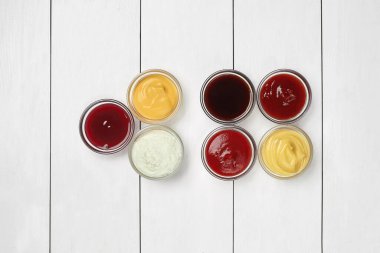 Glass bowls with dipping sauces on white wooden surface