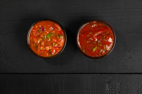 Томатні соуси в скляних мисках на чорному дерев'яному фоні — стокове фото